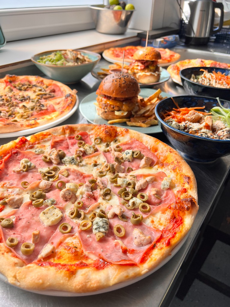 Výber pizzy, burgerov a zdravých misiek na stole kuchyne — Alcatraz, Trenčín